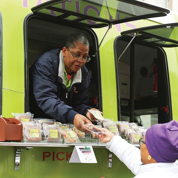 ‘Mobile Soul Sunday’':Teresa Rogers leans out of the window of her food truck business, Sweet Temptations by Teresa, to sell a sweet treat to Evangeline Wood of Ashland on Sunday on Hull Street. Ms. Rogers’ food truck was among 15 in South Side for “Mobile Soul Sunday,” the kickoff of the 2019 Richmond Black Restaurant Week Experience. The event, which runs through Sunday, March 10, highlights Richmond’s black-owned restaurants, food truck and cart operators, caterers and local chefs. (Regina H. Boone/Richmond Free Press)