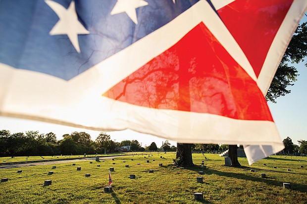 A Confederate battle flag flies over gravesites at the well-maintained Confederate section of Oakwood Cemetery in Richmond. For decades, the state has provided taxpayer money to maintain Confederate graves at the city-owned cemetery.