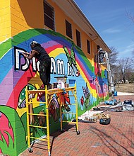 Sir James Thornhill, left, and assistant Michael Rezek put the finishing touches on his “Dream Big” mural that now decorates the Ann Hardy Plaza Community Center in Highland Park in North Side. Best known for the murals he has created in Jackson Ward, Mr. Thornhill was commissioned by the city Department of Parks, Recreation and Community Facilities to create the mural. It adds a bright touch to the park and building which the city has paid more than $1.5 million to renovate and upgrade. The center, named for the late children’s advocate who ran tutoring and preschool programs for years, includes a meeting room, computer lab and a multipurpose space for indoor recreation. (Jeremy M. Lazarus/Richmond Free Press)