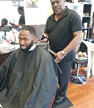 Mr. Barney cuts a customer’s hair in his barbershop in Richmond.