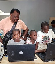 Mr. Barney watches as Haitian youths use the laptops he took to Pignon.