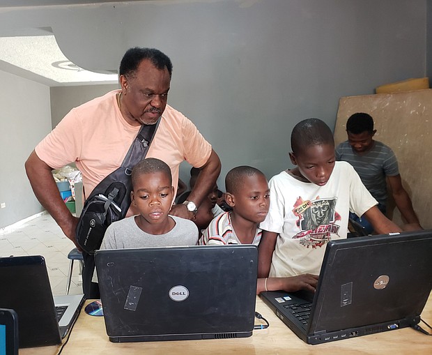 Mr. Barney watches as Haitian youths use the laptops he took to Pignon.