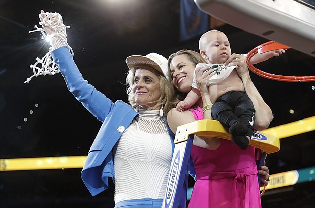 Baylor head coach Kim Mulkey, left, waves the net while standing with daughter and assistant coach Makenzie Fuller and Fuller's son, Kannon Reid Fuller, after winning the national championship over Notre Dame.