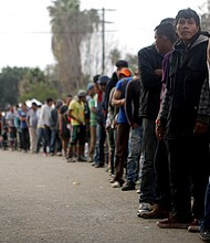 Members of the 'migrant caravan' wait in line to receive breakfast outside a temporary shelter set up for members of the caravan on November 24, 2018 in Tijuana, Mexico.