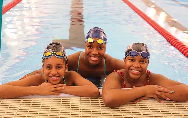 Aquatic dreams: Cherish Daily, left, and T’Mya Harrison, right, sixth-grade and eighth-grade students, respectively, at Richmond’s Franklin Military Academy, pose with Olympic medalist Simone Manuel Tuesday during Splash Day at the newly renovated pool at the Salvation Army Boys & Girls Club in the East End. (Regina H. Boone/Richmond Free Press)
