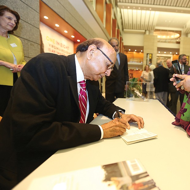 An American story: Khizr Khan of Charlottesville, the father of a U.S. Army captain killed in Iraq in 2004, talked about his new book, “An American Family: A Memoir of Hope and Sacrifice. He appeared April 4 at the Library of Virginia in Downtown as part of the 2019 Carole Weinstein Author Series. He signs a copy of his book for Dr. Paige L. Chargois of Richmond. (Regina H. Boone/Richmond Free Press)