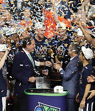 University of Virginia Cavaliers players celebrate their first NCAA Tournament championship win Monday night with Coach Tony Bennett, third from right, on the podium at U.S. Bank Stadium in Minneapolis. The team’s 85-77 victory over Texas Tech came during overtime. It was the first overtime victory in the tournament since 2008 and the eighth in tournament history.