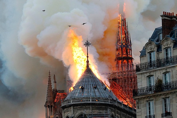 Birds fly away from the Notre Dame cathedral as flames reach the rooftop.