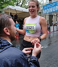 More than 25,000 runners and walkers turned out last Saturday for the annual Monument Avenue 10K. Meredith Celko crosses the Franklin Street finish line, where her waiting boyfriend, Caleb Lunsford, drops to one knee and proposes. He places a ring on her finger. She says yes. (Sandra Sellars/Richmond Free Press)
