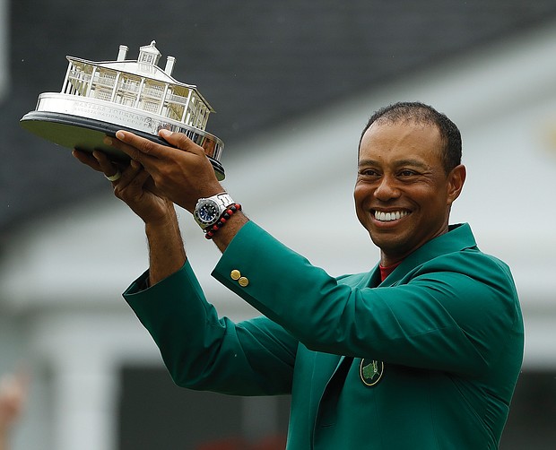 Tiger Woods holds the championship trophy wearing the green jacket donned by winners after coming from behind to claim victory Sunday at the Masters Tournament in Augusta, Ga.