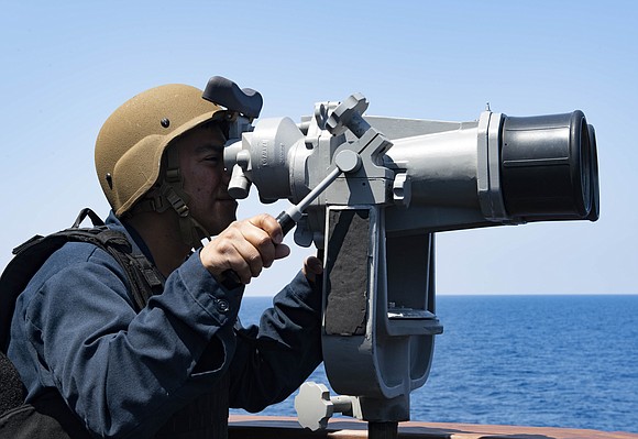 Culinary Specialist 1st Class Samuel Villarreal, from Houston, Texas, uses binoculars while standing watch during a combat systems drill aboard …