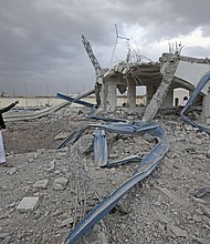 Yemeni man inspects a destroyed petrol station after it was targeted by Saudi-led airstrikes