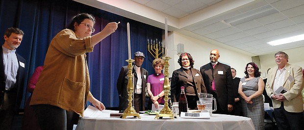 People from many different faiths and backgrounds participate in an interfaith Passover “Justice Seder” Monday evening, using the Exodus story and Passover rituals to shine a light on modern-day oppression of racism, sexism, militarism and materialism. The event was held at Temple Beth-El on Grove Avenue. Above, Miriam Aniel of Richmond Jews for Justice conducts the candle lighting as other faith leaders look on. (Sandra Sellars/Richmond Free Press)