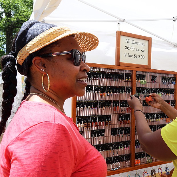 Shopping for wearable art: Dacia Henry, left, and Pat Smith of Richmond peruse earrings made by artist Shirley Hellms of Bremo Bluff during the 48th Annual Arts in the Park last Saturday. More than 450 artists from around the country showed off their work, which was for sale, during the event at the Carillon at Byrd Park. The show is sponsored by the Carillon Civic Association, and attracts painters, potters, photographers, jewelers and other craftspeople. (Regina H. Boone/Richmond Free Press)