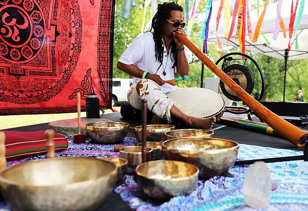 Shanna Latia of Richmond, standing at right, a trained yoga and Himalayan sound bowl therapist, helps Candace Benn of Chester feel the vibrations from the handcrafted Tibetan bowl during the 3rd Annual Peace Love RVA Yoga Festival last Saturday at Maymont. The free festival highlighted the growing yoga community in Richmond and urged compassion and love for all through a full day of free yoga classes and meditation led by area instructors. Music, vegetarian fare and local merchants also were featured, including musician Julian Desta of Richmond, below, who played a didgeridoo. (Regina H. Boone/Richmond Free Press)