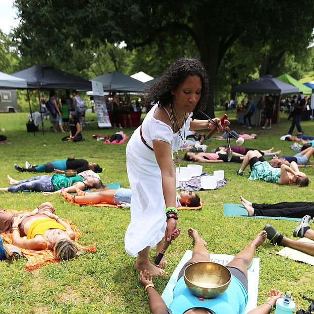 Shanna Latia of Richmond, standing at right, a trained yoga and Himalayan sound bowl therapist, helps Candace Benn of Chester feel the vibrations from the handcrafted Tibetan bowl during the 3rd Annual Peace Love RVA Yoga Festival last Saturday at Maymont. The free festival highlighted the growing yoga community in Richmond and urged compassion and love for all through a full day of free yoga classes and meditation led by area instructors. Music, vegetarian fare and local merchants also were featured, including musician Julian Desta of Richmond, below, who played a didgeridoo. (Regina H. Boone/Richmond Free Press)