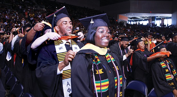 Adrien Passee places the commencement sash over the shoulders of fellow graduate Sara Parsons during the Sunday afternoon ceremony at the Virginia State University Multi-Purpose Center.