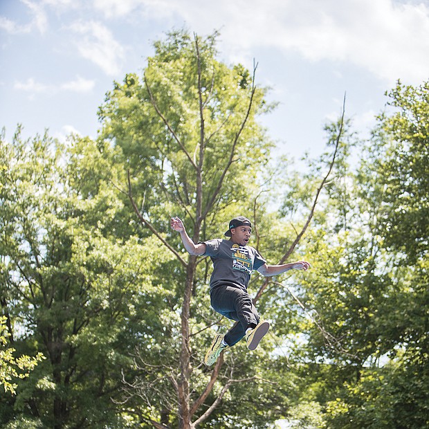 Riverrocking the James/An estimated 100,000 people flocked to Brown’s Island and the riverfront in Downtown last weekend for the Dominion Energy Riverrock festival. The three-day festival featured music, art and a range of sporting events and contests for people and dogs. Aaron Bray takes a leap during a slacklining event. (James Haskins/Richmond Free Press)