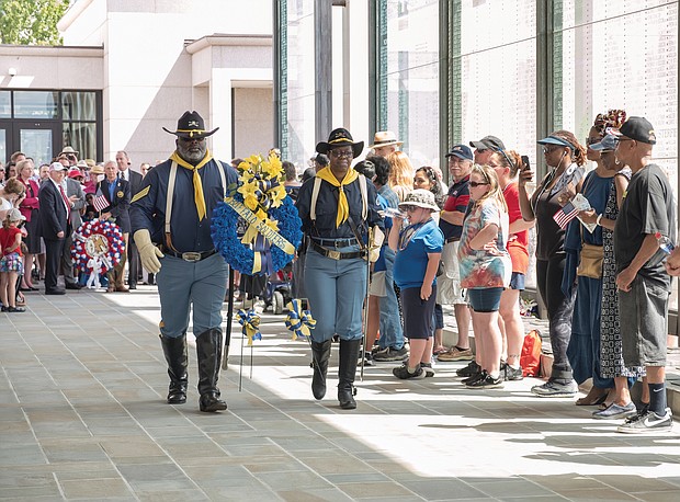 Celebrations of remembrance on Memorial Weekend/
Eddie Rose and Patricia Williams of the Mark Matthews Chapter of Petersburg, 9th and 10th Cavalry of the Buffalo Soldiers Association carry a wreath to be placed at the feet of the statue of Memory during Monday’s 63rd Annual Commonwealth’s Memorial Day Ceremony at the Virginia War Memorial on South Belvidere Street in Downtown. (Ava Reaves/Richmond Free Press)