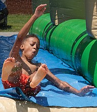 Splashing into the season/
Evan Mayfield, 10, whipped down the water slide Saturday at the 3rd Annual Cookout for a Cause at Westover Hills Elementary School in South Side. The free event, sponsored by Feed the Streets RVA, featured games, arts and crafts, bounce houses, food, music and other activities and vendors for youngsters and families to enjoy. Organizers asked only that each person bring a nonperishable food item to support FeedMore, Central Virginia’s hunger relief organization. Evan, who enjoyed the cool water on a hot day with other young people, attended the event with his mother, Deborah Perry, and his sister, Kaelyn Davis, and her friend, Anna Zohore. (Sandra Sellars/Richmond Free Press)