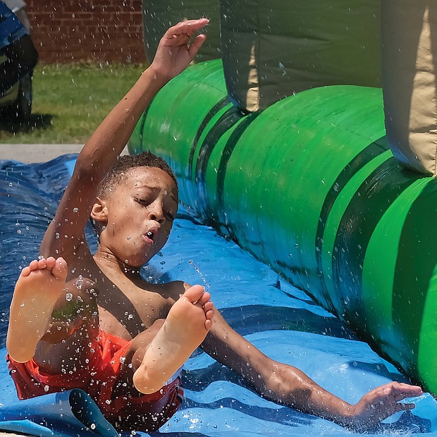 Splashing into the season/
Evan Mayfield, 10, whipped down the water slide Saturday at the 3rd Annual Cookout for a Cause at Westover Hills Elementary School in South Side. The free event, sponsored by Feed the Streets RVA, featured games, arts and crafts, bounce houses, food, music and other activities and vendors for youngsters and families to enjoy. Organizers asked only that each person bring a nonperishable food item to support FeedMore, Central Virginia’s hunger relief organization. Evan, who enjoyed the cool water on a hot day with other young people, attended the event with his mother, Deborah Perry, and his sister, Kaelyn Davis, and her friend, Anna Zohore. (Sandra Sellars/Richmond Free Press)