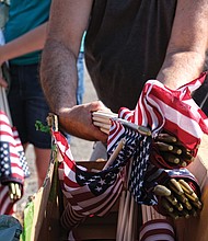 Celebrations of remembrance on Memorial Weekend/
On Saturday, John Harris distributes American flags, above right, to volunteers who placed them beside the graves of veterans buried at historic Evergreen Cemetery in the East End. (Sandra Sellars/Richmond Free Press)