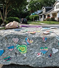 Messages of condolence and love, a tube of bubbles and flowers adorn a boulder at the entrance to Carter Jones Park on Wednesday.