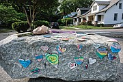 Messages of condolence and love, a tube of bubbles and flowers adorn a boulder at the entrance to Carter Jones Park on Wednesday.