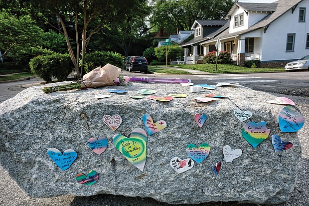 Messages of condolence and love, a tube of bubbles and flowers adorn a boulder at the entrance to Carter Jones Park on Wednesday.