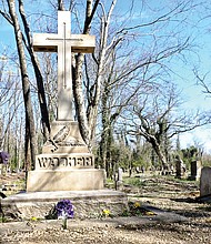Volunteer Brenda Jones plants flowers at Maggie L. Walker’s gravesite in this March 11, 2017, photo of work being done to restore and improve Evergreen Cemetery after decades of neglect.
