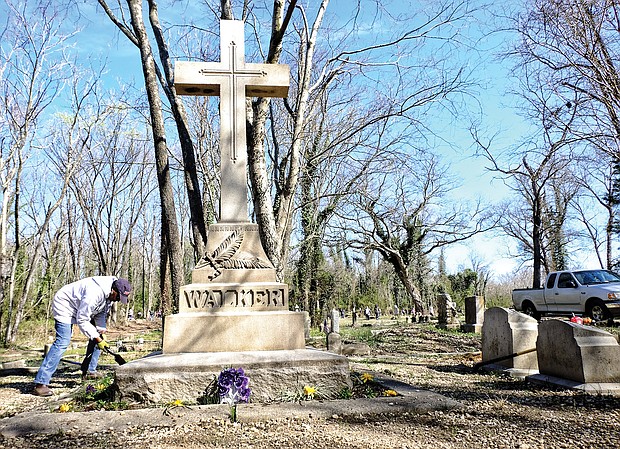 Volunteer Brenda Jones plants flowers at Maggie L. Walker’s gravesite in this March 11, 2017, photo of work being done to restore and improve Evergreen Cemetery after decades of neglect.