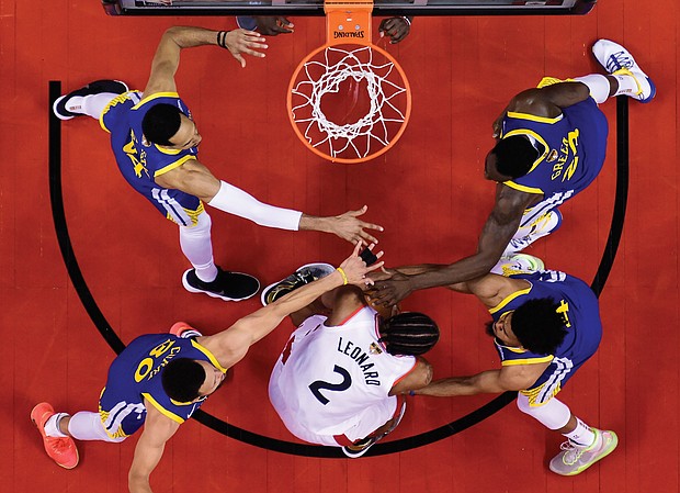 Kawhi Leonard of the Toronto Raptors, wearing the No. 2 jersey, is surrounded by Golden State Warriors’ defenders Shaun Livingston, No. 34; Steph Curry, No. 30; Quinn Cook, No. 4; and Draymond Green, No. 23, during the second half of Sunday’s Game 2 of the NBA Finals.