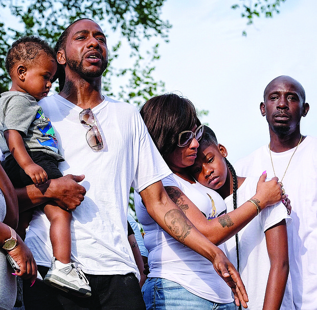 The family of 9-year-old Markiya Dickson grieves during a vigil June 6 at Carter Jones Park, where the youngster was shot and killed. They are, from left, her dad, Mark Whitfield Sr., who is holding young Mark Jr.; mother Ciara Dickson; sister Samaya Dickson; and uncle Dion Tuell. (Sandra Sellars/Richmond Free Press)