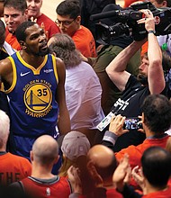 Golden State Warriors forward Kevin Durant, No. 35, glances up at the stands as he is helped off the court Monday night after sustaining an injury to his Achilles tendon during Game 5 of the NBA Finals.