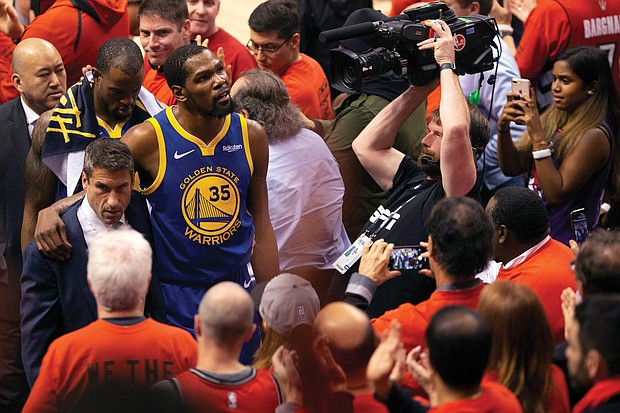 Golden State Warriors forward Kevin Durant, No. 35, glances up at the stands as he is helped off the court Monday night after sustaining an injury to his Achilles tendon during Game 5 of the NBA Finals.