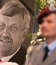 An honor guard stands at a portrait and coffin of murdered German politician Walter Lübcke.