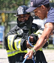 Learning the ropes/
Many youngsters dream of being firefighters when they grow up. Ralph Lee Harris III got to live out the dream during Richmond Fire Station 21’s Community Day event last Saturday at the station, 2505 Jefferson Davis Highway. Dressed out, the youngster helps Firefighter Brianna Robinson of Engine Co. 11 during a hose drill. (Sandra Sellars/Richmond Free Press)