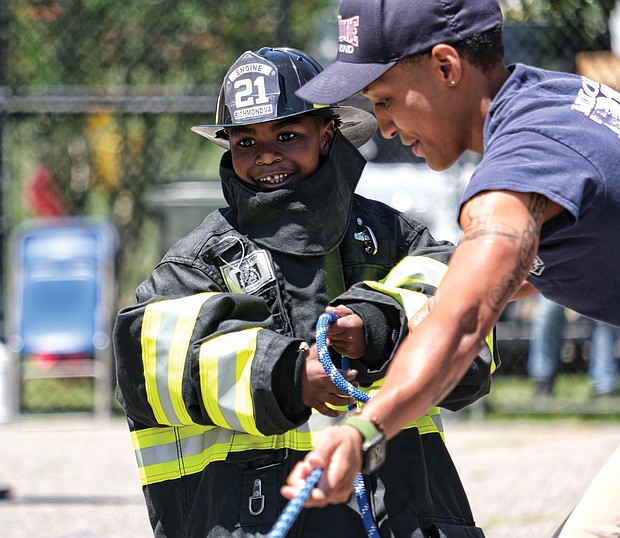 Learning the ropes/
Many youngsters dream of being firefighters when they grow up. Ralph Lee Harris III got to live out the dream during Richmond Fire Station 21’s Community Day event last Saturday at the station, 2505 Jefferson Davis Highway. Dressed out, the youngster helps Firefighter Brianna Robinson of Engine Co. 11 during a hose drill. (Sandra Sellars/Richmond Free Press)