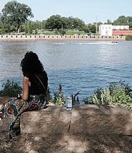 Hundreds of people enjoy activities last Saturday at “Juneteenth: A Freedom Celebration” on the waterfront of the James River in South Side at the Manchester Dock. The three-day event, organized by the Elegba Folklore Society and its founder, Janine Y. Bell, marks the date on June 19, 1865, when enslaved people in Texas learned of their freedom after the defeat of the Confederates and Union forces took control of that state. Richmond’s celebration included educational sessions for people of all ages to learn about Africans brought to this nation 400 years ago and their struggles and contributions. At Saturday’s events, called “Independence Day Our Way,”  Mary Williams sits in reflection at the site, which once served as a landing point for slave ships on the James River. (Sandra Sellars/Richmond Free Press).