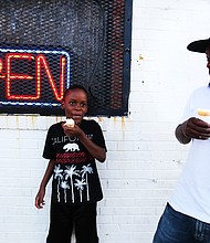 ‘In The Sun Again’
At the Robinson Theater Community Arts Center’s “In The Sun Again Community Block Party” last Friday at the Church Hill center, Jameer Dickerson, 8, and his dad, Ken Dickerson, enjoy ice cream cones at the party. The block party continues the theater’s efforts to be a place that creates connections between residents and supports diversity and inclusion.