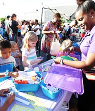 ‘In The Sun Again’
At the Robinson Theater Community Arts Center’s “In The Sun Again Community Block Party” last Friday at the Church Hill, Karen Wells, right, introduces children to art activities at the PBS “Ready to Learn” table in her role as East End manager for the PBS program. The block party continues the theater’s efforts to be a place that creates connections between residents and supports diversity and inclusion. (Regina H. Boone/Richmond Free Press)