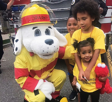 Portland Fire mascot Sparky has a big hello for young Good in the Hood Parade participants Deandre Perez, Jamar Tarver and Korie Washington Ta.