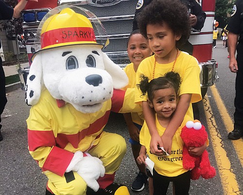 Portland Fire mascot Sparky has a big hello for young Good in the Hood Parade participants Deandre Perez, Jamar Tarver and Korie Washington Ta.