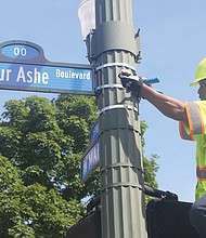 Richmond Department of Public Works employee Malik Mujahid installs one of the many new Arthur Ashe Boulevard signs at the renamed thoroughfare’s intersection with Main Street following the official dedication ceremony. (Sandra Sellars/Richmond Free Press)