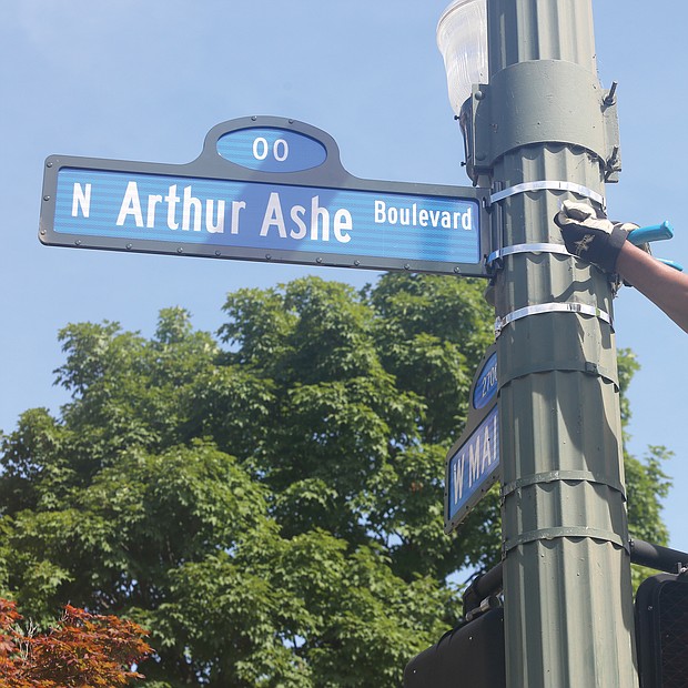 Richmond Department of Public Works employee Malik Mujahid installs one of the many new Arthur Ashe Boulevard signs at the renamed thoroughfare’s intersection with Main Street following the official dedication ceremony. (Sandra Sellars/Richmond Free Press)