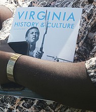 A guest at the official dedication of Arthur Ashe Boulevard holds a water bottle and brochure about Arthur Ashe Jr., who is part of the Virginia Museum of History & Culture’s current exhibit, “Determined: The 400-Year Struggle for Black Equality.” (Regina H. Boone/Richmond Free Press)