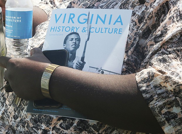 A guest at the official dedication of Arthur Ashe Boulevard holds a water bottle and brochure about Arthur Ashe Jr., who is part of the Virginia Museum of History & Culture’s current exhibit, “Determined: The 400-Year Struggle for Black Equality.” (Regina H. Boone/Richmond Free Press)