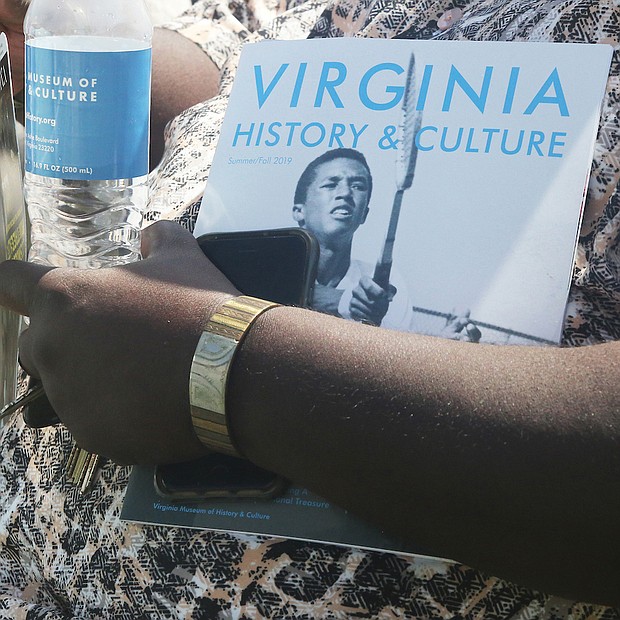 A guest at the official dedication of Arthur Ashe Boulevard holds a water bottle and brochure about Arthur Ashe Jr., who is part of the Virginia Museum of History & Culture’s current exhibit, “Determined: The 400-Year Struggle for Black Equality.” (Regina H. Boone/Richmond Free Press)