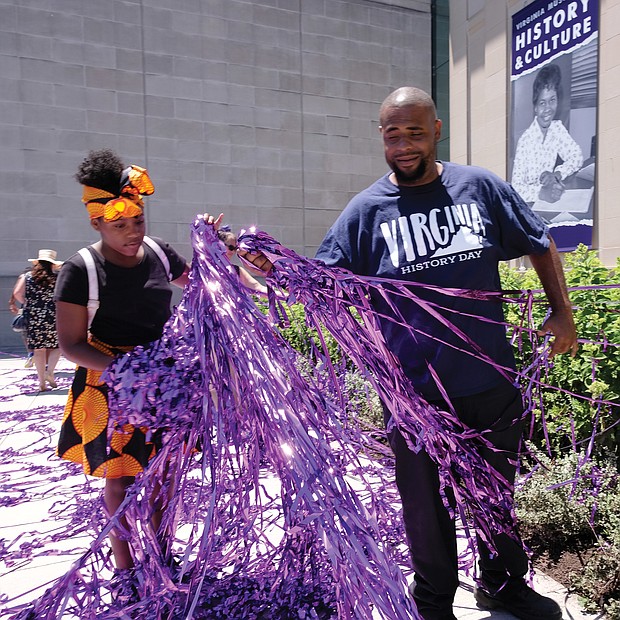 12-year-old Yaa-Nailah Bell-Barber and her uncle, Brian Wright, collect some of the purple streamers launched at the unveiling ceremony. Yaa-Nailah wanted to keep some of the streamers as a souvenir of the historic day. (Regina H. Boone/Richmond Free Press)