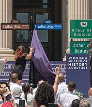 Richmond City Councilwoman Kim B. Gray, 2nd District, pulls down the last curtain to unveil the new Arthur Ashe Boulevard signs as Mr. Ashe’s nephew, David O. Harris Jr., left, and Mayor Levar M. Stoney watch.  (Ava Reaves/Richmond Free Press)